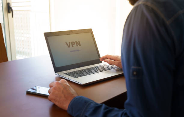 A man using a laptop with the word "VPN" displayed on the screen