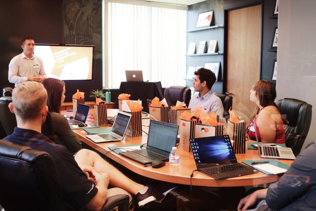 A team meeting around a conference table with their laptops while their manager presents on "What is a real time dashboard."