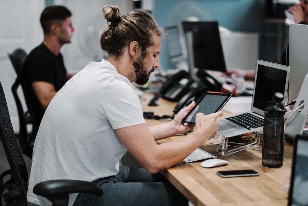 A new data analyst working at a long desk with other people, researching "What is a real time dashboard?"